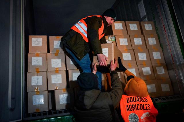 French farmers unload a trck to inspect transport of foreign products, as part of national protests against the EU-Mercosur agreement and the government's handling of the contagious nodular dermatitis (CND) epidemic, on the harbour of Le Havre, northwestern France on January 12, 2026. (Photo by Lou BENOIST / AFP)