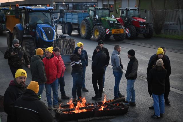 French farmers stand by a fire at the start of their blockade of an oil depot as part of national protests against the EU-Mercosur agreement and the government's handling of the contagious nodular dermatitis (CND) epidemic, on the harbour of La Pallice in La Rochelle, southwestern France on January 12, 2026. (Photo by Christophe ARCHAMBAULT / AFP)