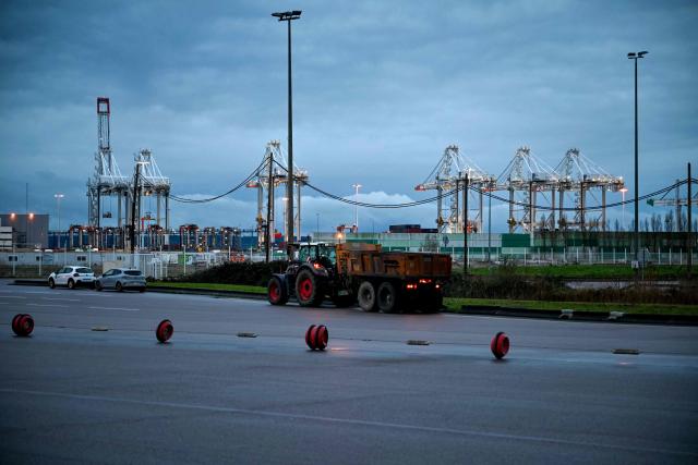 A tractor is parked as farmers inspect transport of foreign products, as part of national protests against the EU-Mercosur agreement and the government's handling of the contagious nodular dermatitis (CND) epidemic, on the harbour of Le Havre, northwestern France on January 12, 2026. (Photo by Lou BENOIST / AFP)
