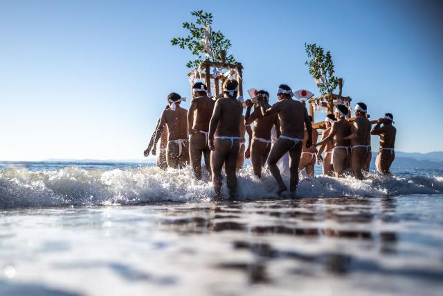 Participants carry a portable shrine "mikoshi" during the winter sea purification festival, an annual new year's event, at a beach in Numazu, Shizuoka Prefecture on January 12, 2026. (Photo by Philip FONG / AFP)