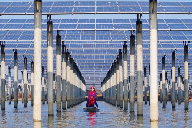 TOPSHOT - Workers check solar panels installed on a lake in Tianchang, east China's Anhui province on January 12, 2026. (Photo by AFP) / China OUT