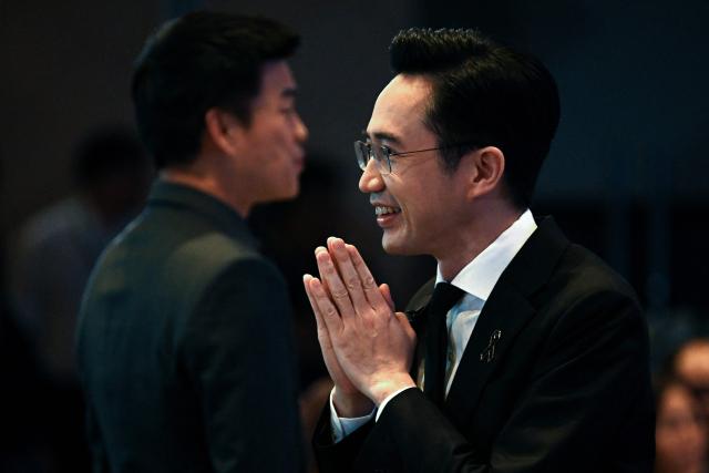 Pheu Thai Party’s prime ministerial candidate Yodchanan Wongsawat greets supporters as People’s Party’s prime ministerial candidate and party leader Natthaphong Ruengpanyawut is seen at the back, at the Global Dynamics and Thailand’s Future event at Queen Sirikit National Convention Center in Bangkok on January 12, 2026. (Photo by Lillian SUWANRUMPHA / AFP)