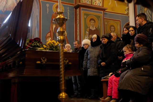 Relatives, friends and others mourn at the coffin of Sergiy Smolyak, a medic who died as a result of repeated Russian attacks, during the funeral ceremony at the St. Michael's Golden-Domed Monastery in Kyiv early on January 12, 2026, amid the Russian invasion of Ukraine. (Photo by Tetiana DZHAFAROVA / AFP)