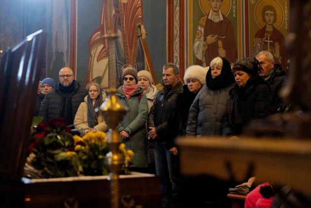 Relatives, friends and others mourn at the coffin of Sergiy Smolyak, a medic who died as a result of repeated Russian attacks, during the funeral ceremony at the St. Michael's Golden-Domed Monastery in Kyiv early on January 12, 2026, amid the Russian invasion of Ukraine. (Photo by Tetiana DZHAFAROVA / AFP)