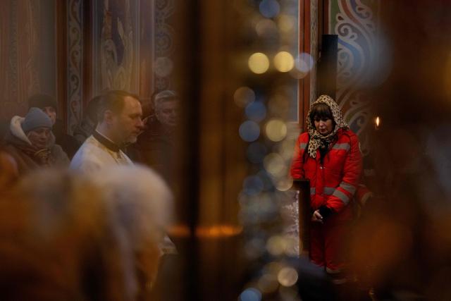 Relatives, friends and others mourn at the coffin of Sergiy Smolyak, a medic who died as a result of repeated Russian attacks, during the funeral ceremony at the St. Michael's Golden-Domed Monastery in Kyiv early on January 12, 2026, amid the Russian invasion of Ukraine. (Photo by Tetiana DZHAFAROVA / AFP)