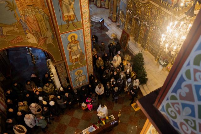 Relatives, friends and others mourn at the coffin of Sergiy Smolyak, a medic who died as a result of repeated Russian attacks, during the funeral ceremony at the St. Michael's Golden-Domed Monastery in Kyiv early on January 12, 2026, amid the Russian invasion of Ukraine. (Photo by Tetiana DZHAFAROVA / AFP)