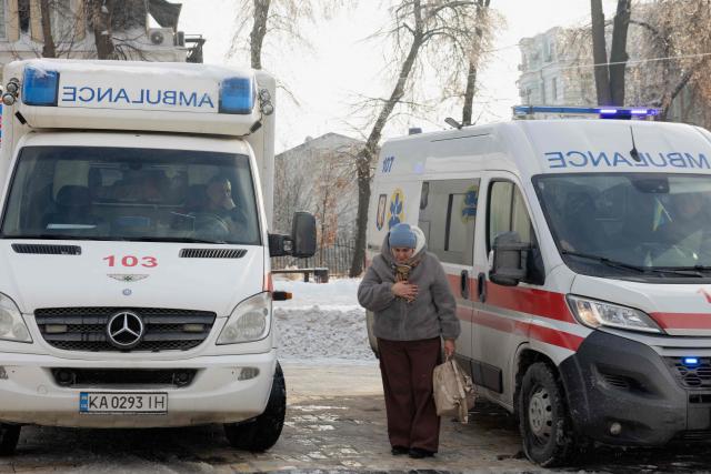 A woman mourns near ambulances during the funeral ceremony of Sergiy Smolyak, a medic who died as a result of repeated Russian attacks,  outside the St. Michael's Golden-Domed Monastery in Kyiv early on January 12, 2026, amid the Russian invasion of Ukraine. (Photo by Tetiana DZHAFAROVA / AFP)