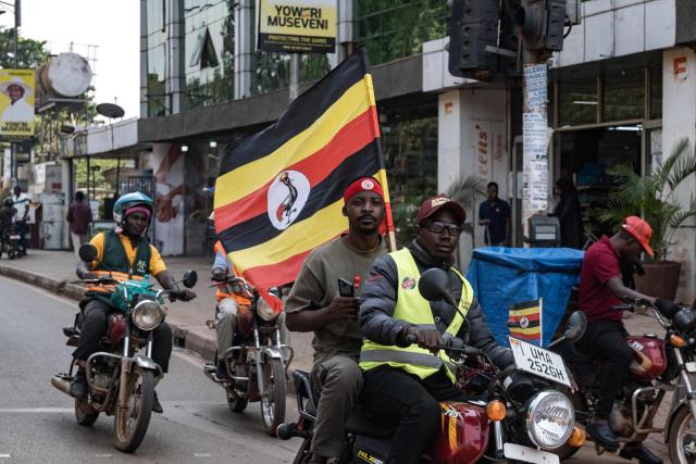 Motorcyclists holding a Ugandan flag drive in the road ahead of the final rally of opposition leader and presidential candidate for the National Unity Platform (NUP) Robert Kyagulanyi Ssentamu, popularly known as Bobi Wine, in Kampala, on January 12, 2026. (Photo by Badru Katumba / AFP)