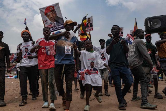 Supporters of opposition leader and presidential candidate for the National Unity Platform (NUP) Robert Kyagulanyi Ssentamu, popularly known as Bobi Wine, hold banners and flags as they chant slogans during his final presidential campaign rally in Kampala, on January 12, 2026. (Photo by Badru Katumba / AFP)