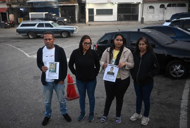 Relatives of inmates hold signs of their beloved ones, outside El Rodeo I prison in Guatire, Miranda State, some 30 kilometers east of Caracas on January 12, 2026. Venezuela said that 116 political prisoners have been released since the government announced last week it would begin freeing those jailed under president Nicolas Maduro, who was seized by US forces in a raid on Caracas. (Photo by Federico PARRA / AFP)