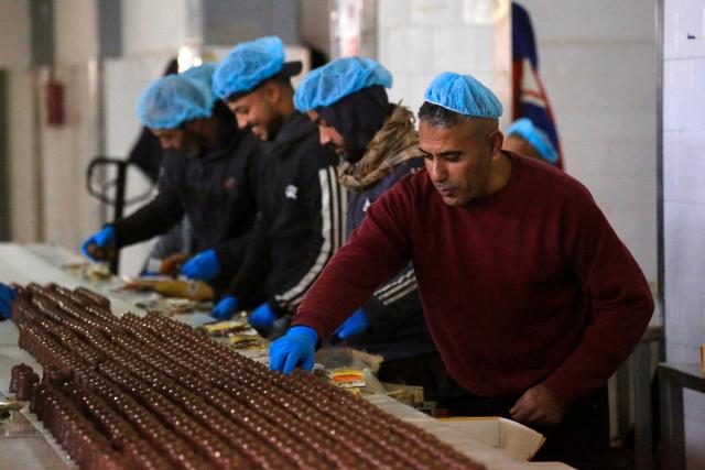 Palestinian workers inspect sweet locally known as "al-Shatwi" (Winter) Crimbo sweets, as the Al-Arees factory gradually resumes operations after a hiatus caused by the Gaza war which led to shortages of raw materials used in their products, in Deir al-Balah, in the central Gaza Strip on January 12, 2026, following a US-brokered truce that halted the two-year war. (Photo by Bashar Taleb / AFP)