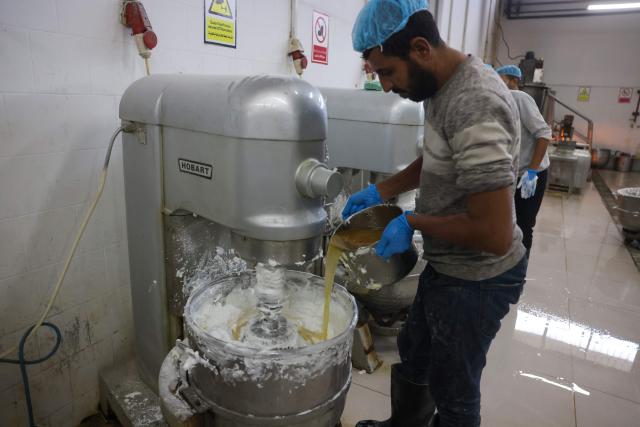 Palestinian employees prepare the filler of the sweet locally known as "al-Shatwi" (Winter) Crimbo sweets, as the Al-Arees factory gradually resumes operations after a hiatus caused by the Gaza war which led to shortages of raw materials used in their products, in Deir al-Balah, in the central Gaza Strip on January 12, 2026, following a US-brokered truce that halted the two-year war. (Photo by Bashar Taleb / AFP)
