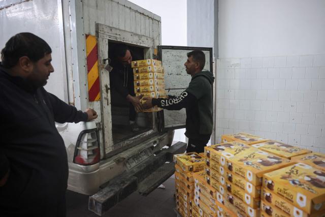 Palestinian employees moves boxes of sweets locally known as "al-Shatwi" (Winter) Crimbo sweets, ready for the local market, as the Al-Arees factory gradually resumes operations after a hiatus caused by the Gaza war which led to shortages of raw materials used in their products, in Deir al-Balah, in the central Gaza Strip on January 12, 2026, following a US-brokered truce that halted the two-year war. (Photo by Bashar Taleb / AFP)