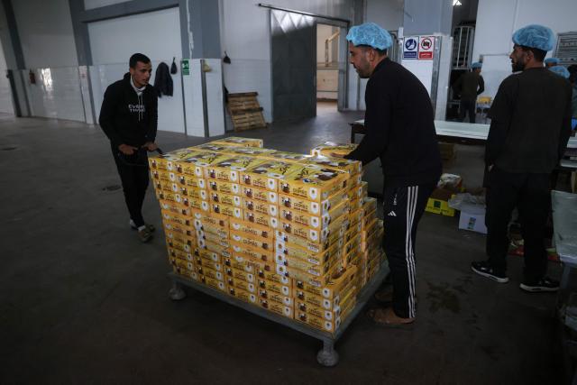 Palestinian employees moves boxes of sweets locally known as "al-Shatwi" (Winter) Crimbo sweets, ready for the local market, as the Al-Arees factory gradually resumes operations after a hiatus caused by the Gaza war which led to shortages of raw materials used in their products, in Deir al-Balah, in the central Gaza Strip on January 12, 2026, following a US-brokered truce that halted the two-year war. (Photo by Bashar Taleb / AFP)