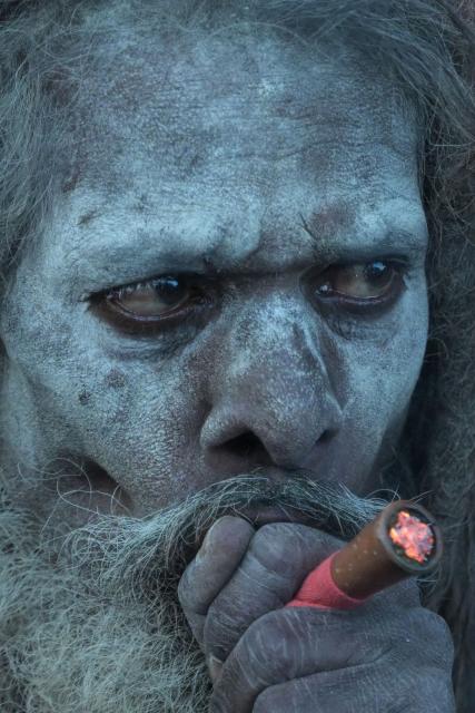 A sadhu or a Hindu holyman smokes using a traditional clay pipe at a transit camp, ahead of the upcoming Hindu festival 'Gangasagar Mela', in Kolkata on January 12, 2026. (Photo by Dibyangshu SARKAR / AFP)