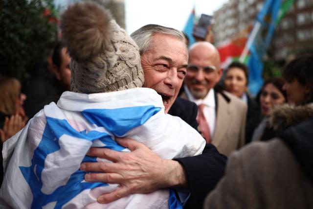 Reform UK leader, Nigel Farage embraces an anti-Iranian regime protester wearing an israeli flag during a gathering outside the Iranian Embassy, central London, on January 12, 2026. (Photo by HENRY NICHOLLS / AFP)