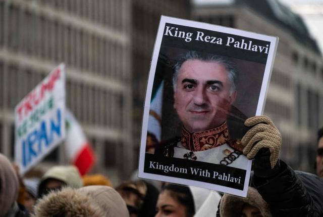 A demonstrator displays a placard featuring a portrait of Reza Pahlavi, the son of Iran's late ruler Mohammad Reza Pahlavi, during an anti-Iranian-government protest in front of the Brandenburg Gate in Berlin, Germany, on January 12, 2026. (Photo by John MACDOUGALL / AFP)