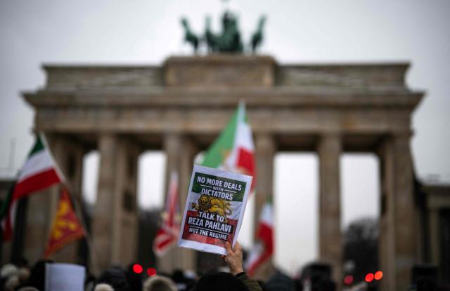 A demonstrator displays a placard calling for the return of Reza Pahlavi, the son of Iran's late ruler Mohammad Reza Pahlavi during an anti-Iranian-government protest in front of the Brandenburg Gate in Berlin, Germany, on January 12, 2026. (Photo by John MACDOUGALL / AFP)