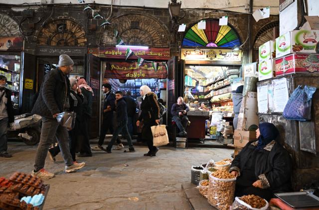 Syrians walk in the Al-Bazouriya market in Old Damascus on January 12, 2026. (Photo by LOUAI BESHARA / AFP)
