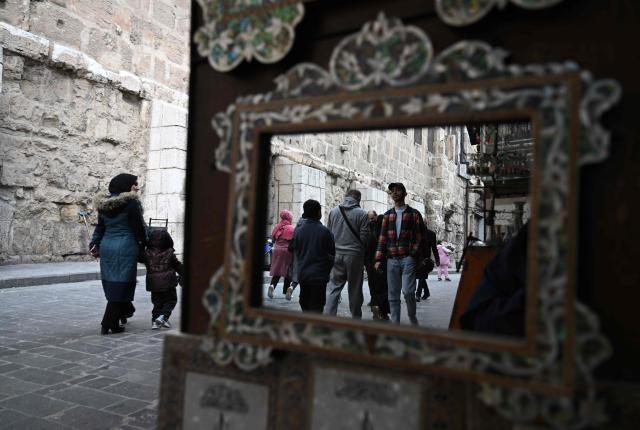 Syrians walk in the market in Old Damascus on January 12, 2026. (Photo by LOUAI BESHARA / AFP)