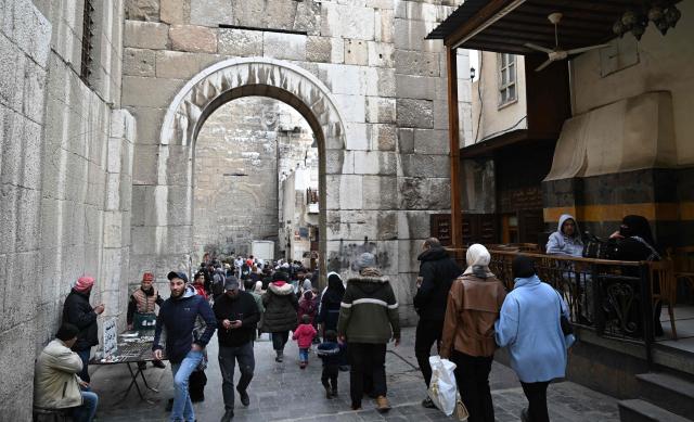 Syrians walk down a street behind the Umayyad Mosque in Old Damascus on January 12, 2026. (Photo by LOUAI BESHARA / AFP)