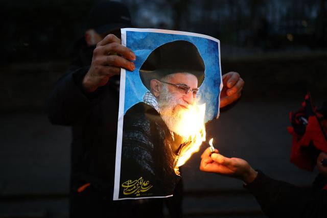 Anti-Iranian regime protesters burn an image of Ayatollah Ali Khamenei, during a gathering outside the Iranian Embassy, central London, on January 12, 2026. (Photo by Henry NICHOLLS / AFP)