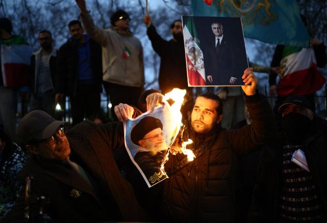 Anti-Iranian regime protesters burn an image of Ayatollah Ali Khamenei, while holding aloft a placard featuring an image of Iranian opposition figure and son of the last Shah of Iran, Reza Pahlav, during a gathering outside the Iranian Embassy, central London, on January 12, 2026. (Photo by Henry NICHOLLS / AFP)