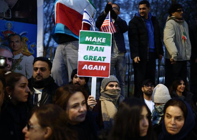Anti-Iranian regime protesters wave Iranian flags during a gathering outside the Iranian Embassy, central London, on January 12, 2026. (Photo by Henry NICHOLLS / AFP)