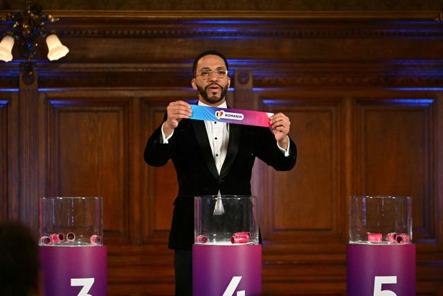Moderator Austrian singer Cesar Sampson holds a draw for Romania during the draw session for the two semi-final events of the Eurovision Song Contest 2026 on stage at the Vienna’s city hall in Vienna, Austria, on January 12, 2026. Vienna hosts the Eurovision Song Contest 2026 on May 12-14. (Photo by Joe Klamar / AFP)
