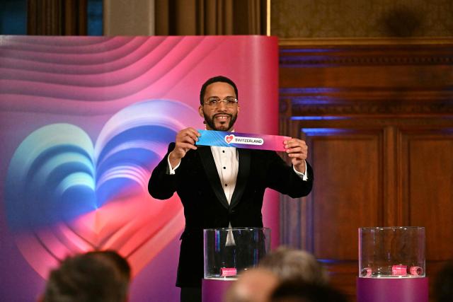 Moderator Austrian singer Cesar Sampson holds a draw for Switzerland during the draw session for the two semi-final events of the Eurovision Song Contest 2026 on stage at the Vienna’s city hall in Vienna, Austria, on January 12, 2026. Vienna hosts the Eurovision Song Contest 2026 on May 12-14. (Photo by Joe Klamar / AFP)