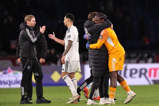 Paris FC's French goalkeeper #01 Obed Nkambadio (R) celebrates with team members after winning their French Cup round of 32 football match between against Paris Saint-Germain (PSG) at the Parc des Princes stadium in Paris on January 12, 2026. (Photo by Anne-Christine POUJOULAT / AFP)