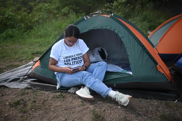 A relative of inmates checks her mobile phone while waiting for news about the release of prisoners outside El Rodeo I prison in Guatire, Miranda State, some 30 kilometers east of Caracas on January 12, 2026. Venezuela said that 116 political prisoners have been released since the government announced last week it would begin freeing those jailed under president Nicolas Maduro, who was seized by US forces in a raid on Caracas. (Photo by Federico PARRA / AFP)