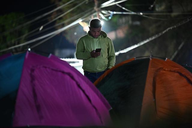 A relative of inmates checks his mobile phone while waiting for news about the release of prisoners outside El Rodeo I prison in Guatire, Miranda State, some 30 kilometers east of Caracas on January 12, 2026. Venezuela said that 116 political prisoners have been released since the government announced last week it would begin freeing those jailed under president Nicolas Maduro, who was seized by US forces in a raid on Caracas. (Photo by Federico PARRA / AFP)