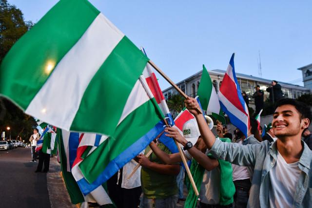 Supporters of Costa Rica's presidential candidate Alvaro Ramos of the Partido Liberacion  (PLN) wave flags of their party during a debate outside the Supreme Electoral Tribunal (TSE) in San Jose, Costa Rica on January 12, 2026. Costa Rica will hold presidential election on February 1. (Photo by EZEQUIEL BECERRA / AFP)
