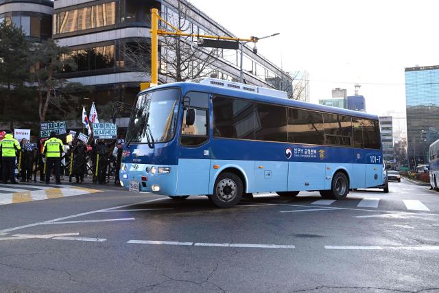 A blue bus believed to be transporting South Korea's impeached former president Yoon Suk Yeol arrives at the Seoul Central District Court in Seoul on January 13, 2026, as Yoon's final criminal trial on insurrection charges is scheduled to be held in the court. (Photo by Jung Yeon-je / AFP)