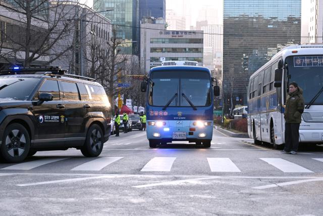 A blue bus believed to be transporting South Korea's impeached former president Yoon Suk Yeol arrives at the Seoul Central District Court in Seoul on January 13, 2026, as Yoon's final criminal trial on insurrection charges is scheduled to be held in the court. (Photo by Jung Yeon-je / AFP)