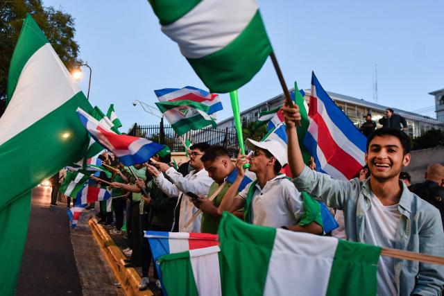 Supporters of Costa Rica's presidential candidate Alvaro Ramos of the Partido Liberacion  (PLN) wave flags of their party during a debate outside the Supreme Electoral Tribunal (TSE) in San Jose, Costa Rica on January 12, 2026. Costa Rica will hold presidential election on February 1. (Photo by EZEQUIEL BECERRA / AFP)