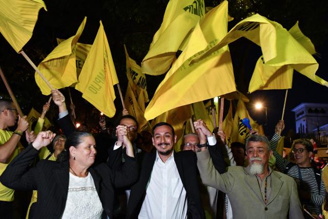 Costa Rica's presidential candidate Ariel Robles (C) of the Frente Amplio Party (FA) poses for pictures with supporters as he arrives for a debate outside the Supreme Electoral Tribunal (TSE) in San Jose, Costa Rica on January 12, 2026. Costa Rica will hold presidential election on February 1. (Photo by EZEQUIEL BECERRA / AFP)