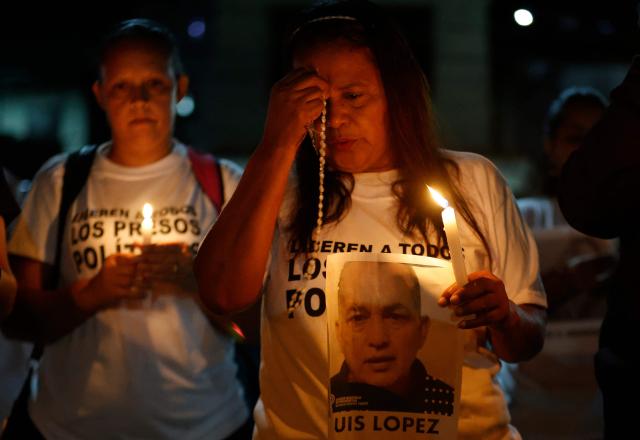 Relatives of political prisoners pray during a candle vigil outside El Rodeo I prison in Guatire, Miranda State, some 30 kilometers east of Caracas on January 12, 2026. Venezuela said January 12, it had freed dozens more political prisoners as rights groups questioned the numbers and family members clamored for speedier releases after the US military ouster of long-term autocrat Nicolas Maduro. (Photo by Pedro MATTEY / AFP)