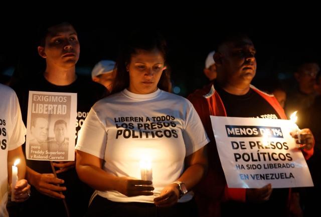 Relatives of political prisoners pray during a candle vigil outside El Rodeo I prison in Guatire, Miranda State, some 30 kilometers east of Caracas on January 12, 2026. Venezuela said January 12, it had freed dozens more political prisoners as rights groups questioned the numbers and family members clamored for speedier releases after the US military ouster of long-term autocrat Nicolas Maduro. (Photo by Pedro MATTEY / AFP)