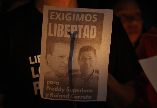 A man holds a poster with the image of political prisoners during a candle vigil outside El Rodeo I prison in Guatire, Miranda State, some 30 kilometers east of Caracas on January 12, 2026. Venezuela said January 12, it had freed dozens more political prisoners as rights groups questioned the numbers and family members clamored for speedier releases after the US military ouster of long-term autocrat Nicolas Maduro. (Photo by Pedro MATTEY / AFP)