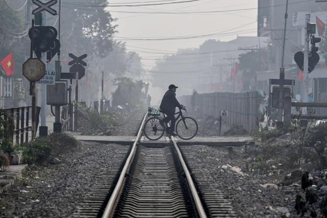 A man rides his bicycle across railway tracks in Hanoi on January 13, 2026. (Photo by Nhac NGUYEN / AFP)