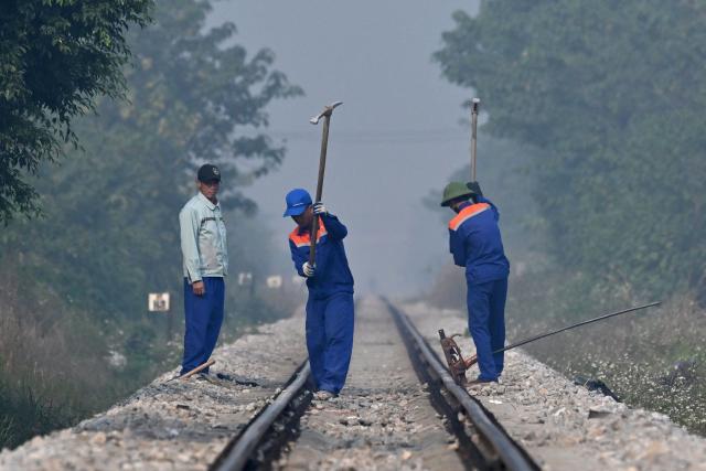 Labourers work on railway tracks in Hanoi on January 13, 2026. (Photo by Nhac NGUYEN / AFP)