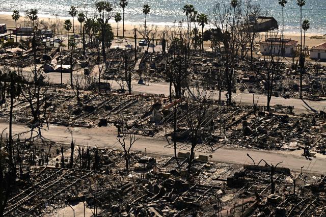 (FILES) Charred homes and burnt cars are pictured amid the rubble of the fire-ravaged Pacific Palisades Bowl Mobile Estates in Los Angeles, California, on January 13, 2025. Global natural disaster losses dropped sharply to $224 billion in 2025, reinsurer Munich Re said on January 13, 2026, but warned of a still "alarming" picture of extreme weather events driven by climate change. (Photo by AGUSTIN PAULLIER / AFP)