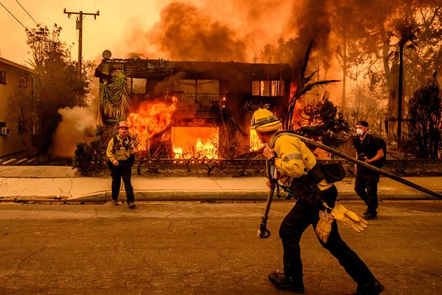 (FILES) Firefighters work the scene as an apartment building burns during the Eaton fire in the Altadena area of Los Angeles county, California on January 8, 2025. Global natural disaster losses dropped sharply to $224 billion in 2025, reinsurer Munich Re said on January 13, 2026, but warned of a still "alarming" picture of extreme weather events driven by climate change. (Photo by JOSH EDELSON / AFP)
