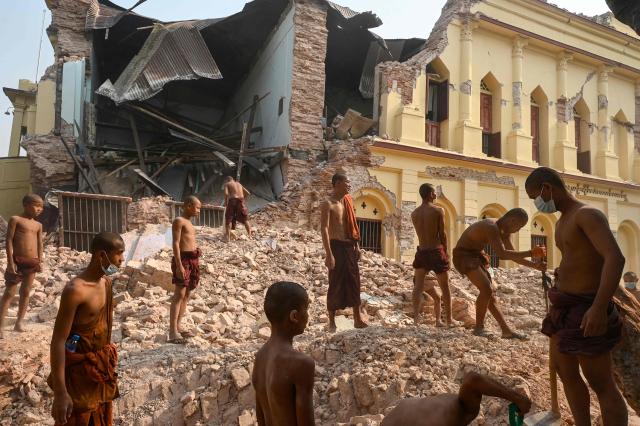 (FILES) Buddhist monks stand on rubble as they clear up debris at the damaged Thahtay Kyaung Monastery in Mandalay on April 1, 2025, four days after a major earthquake struck central Myanmar. Global natural disaster losses dropped sharply to $224 billion in 2025, reinsurer Munich Re said on January 13, 2026, but warned of a still "alarming" picture of extreme weather events driven by climate change. (Photo by Sai Aung MAIN / AFP)