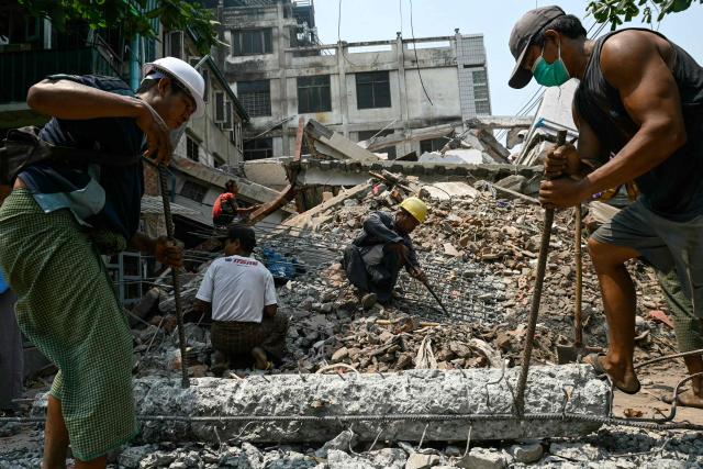 (FILES) Workers clear up the rubble of a collapsed building in Mandalay on April 2, 2025, five days after a major earthquake struck central Myanmar. Global natural disaster losses dropped sharply to $224 billion in 2025, reinsurer Munich Re said on January 13, 2026, but warned of a still "alarming" picture of extreme weather events driven by climate change. (Photo by Sai Aung MAIN / AFP)