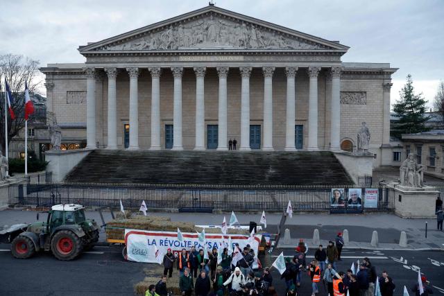 Farmers with unions flags gather in front of the National Assembly during a protest to demand "concrete and immediate action" from the government, which is struggling to deal with the anger of farmers in Paris on January 13, 2026. Called by the FNSEA and "Jeunes Agriculteurs" unions and a few days before the signing of the EU-Mercosur agreement, a convoy of farmers entered the capital early in the morning. (Photo by GEOFFROY VAN DER HASSELT / AFP)