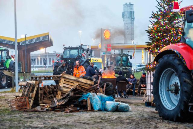 Farmers burn wood near a Shell petrol station during a demonstration as unions called farmers to block several strategic traffic junctions with tractors to protest against EU-Mercosur agreements, near Ostend airport on January 13, 2026. European Commission head will sign the Mercosur trade deal in Paraguay on January 17, 2026. (Photo by KURT DESPLENTER / Belga / AFP) / Belgium OUT
