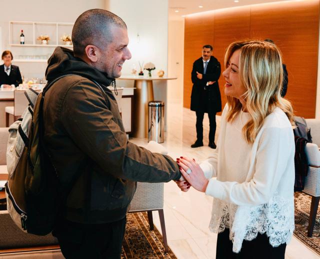 Italia's Prime Minister Giorgia Meloni (R) shakes hands with Italian humanitarian worker Alberto Trentini after his release from Venezuela, as he arrives at Ciampino Airport in Rome on January 13, 2026. (Photo by Filippo ATTILI / various sources / AFP)